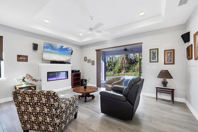 living area featuring light wood-style floors, visible vents, and a raised ceiling