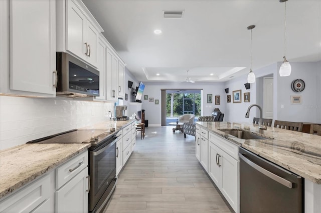 kitchen featuring a sink, visible vents, appliances with stainless steel finishes, backsplash, and a tray ceiling