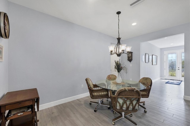 dining room with light wood-type flooring, baseboards, visible vents, and a notable chandelier