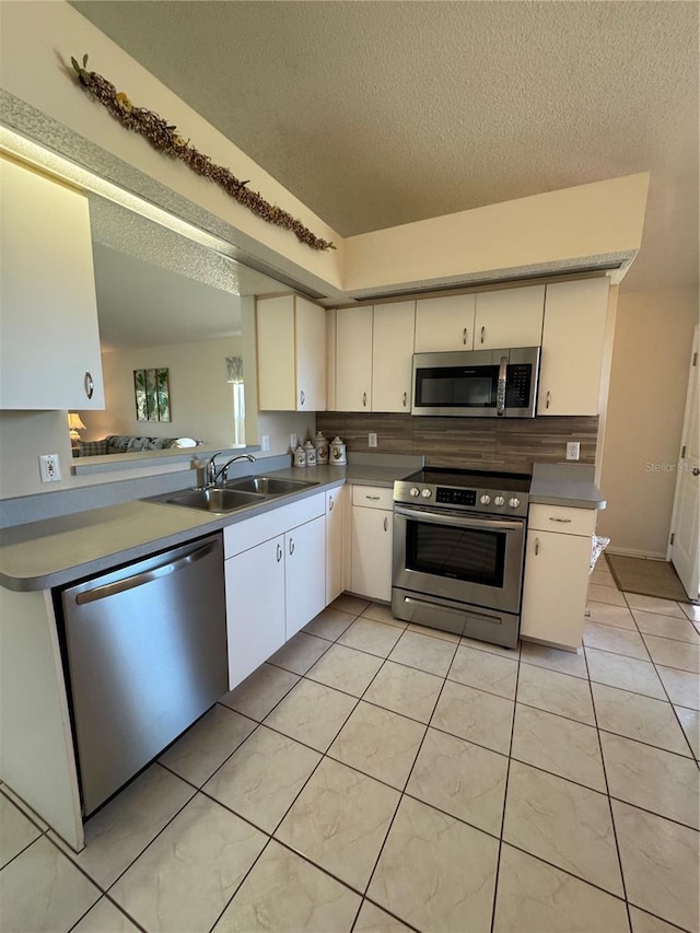 kitchen with light countertops, appliances with stainless steel finishes, a sink, and white cabinetry