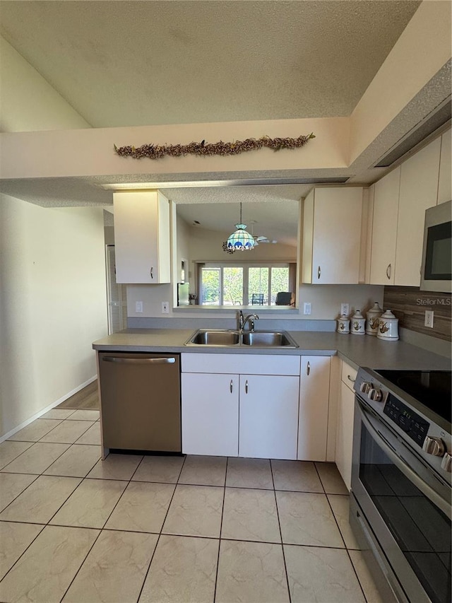 kitchen with a sink, white cabinetry, light countertops, appliances with stainless steel finishes, and pendant lighting