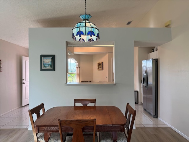 dining room featuring baseboards, a textured ceiling, and light tile patterned flooring