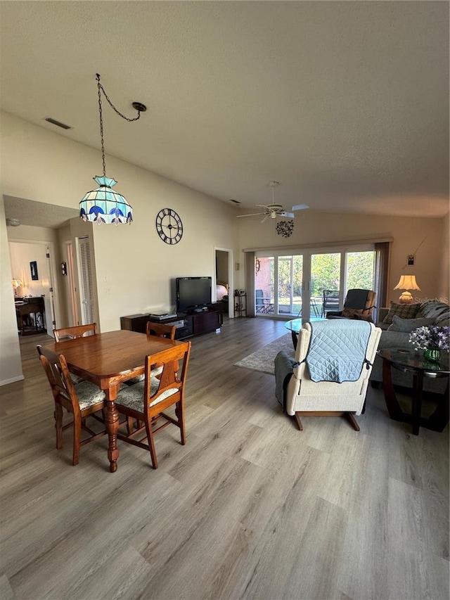 dining space featuring french doors, visible vents, a ceiling fan, vaulted ceiling, and wood finished floors