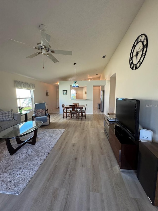 living room featuring vaulted ceiling, ceiling fan, and light wood finished floors