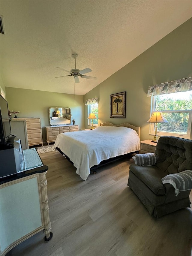 bedroom with light wood-type flooring, multiple windows, and vaulted ceiling