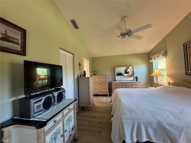 bedroom featuring lofted ceiling, a textured ceiling, wood finished floors, and visible vents