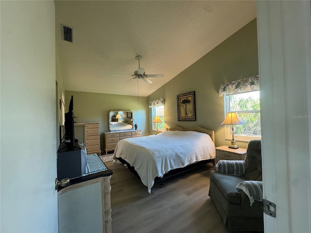 bedroom with lofted ceiling, multiple windows, wood finished floors, and visible vents