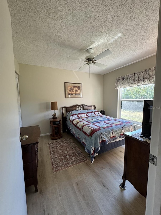 bedroom featuring light wood-style floors, ceiling fan, and a textured ceiling