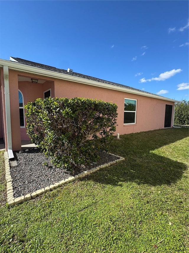 view of side of home with a yard and stucco siding