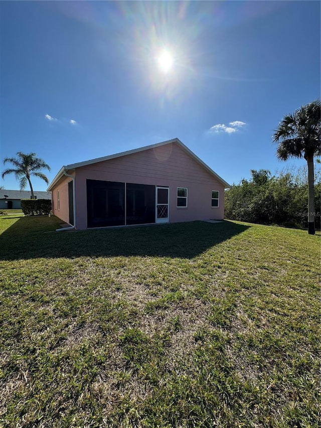 back of property with a yard and a sunroom