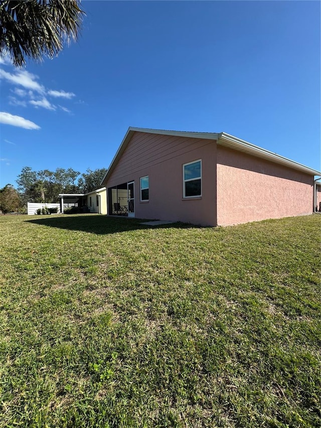 view of side of home with stucco siding and a yard