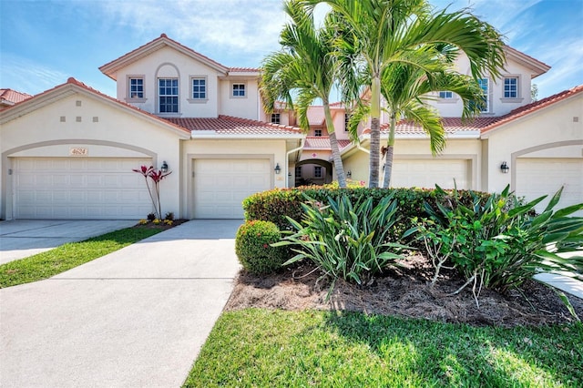 mediterranean / spanish house with driveway, a tiled roof, a garage, and stucco siding