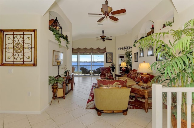 living room featuring light tile patterned floors, a ceiling fan, visible vents, vaulted ceiling, and baseboards