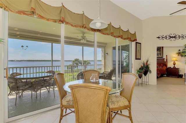 dining space featuring a ceiling fan, a water view, and light tile patterned floors