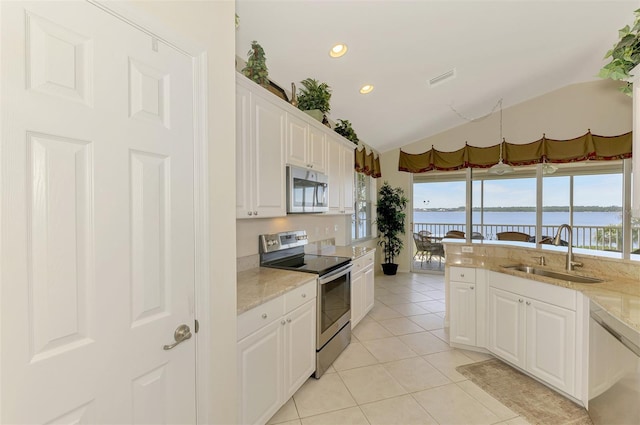 kitchen featuring white cabinets, a water view, stainless steel appliances, a sink, and light tile patterned flooring