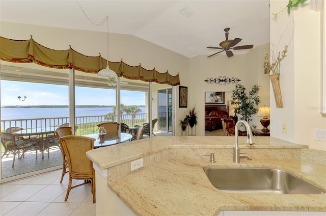 kitchen with ceiling fan, light tile patterned floors, a water view, a sink, and vaulted ceiling