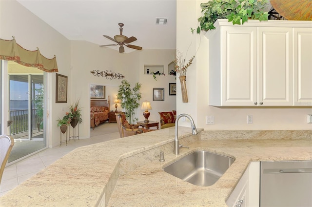 kitchen with visible vents, light stone counters, stainless steel dishwasher, white cabinetry, and a sink