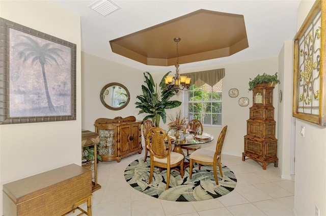 dining space featuring a tray ceiling, visible vents, an inviting chandelier, and light tile patterned floors