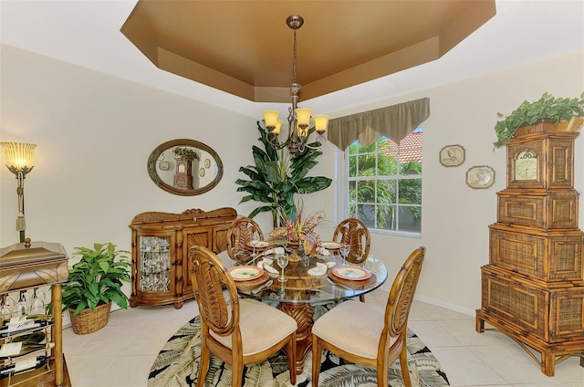 dining room with light tile patterned floors, a tray ceiling, baseboards, and a notable chandelier