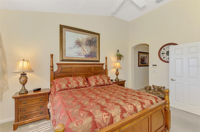 bedroom with arched walkways, light colored carpet, vaulted ceiling, and visible vents