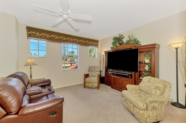 living area featuring light colored carpet, ceiling fan, and baseboards