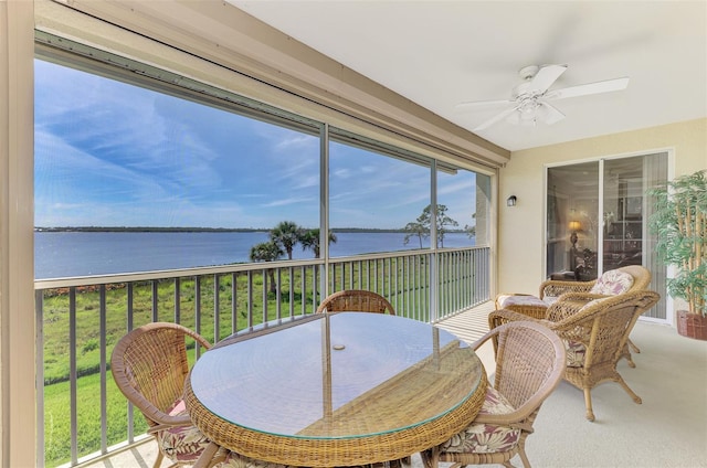 sunroom featuring a water view and a ceiling fan