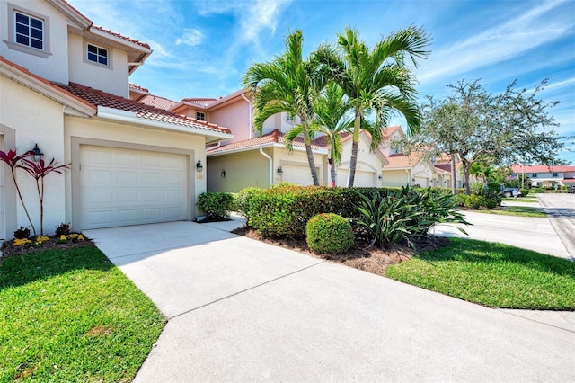 mediterranean / spanish-style house featuring driveway, stucco siding, a residential view, and a tiled roof