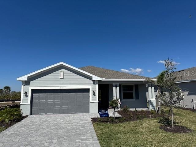 single story home with a front lawn, decorative driveway, and an attached garage