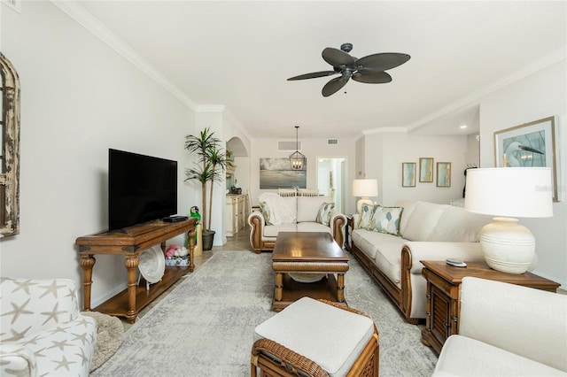 living area featuring a ceiling fan, visible vents, arched walkways, and crown molding