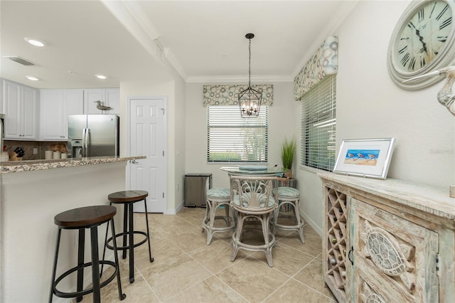 dining space with light tile patterned flooring, crown molding, visible vents, baseboards, and an inviting chandelier