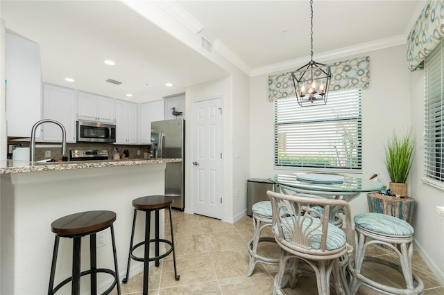 kitchen featuring light stone counters, visible vents, white cabinetry, ornamental molding, and appliances with stainless steel finishes