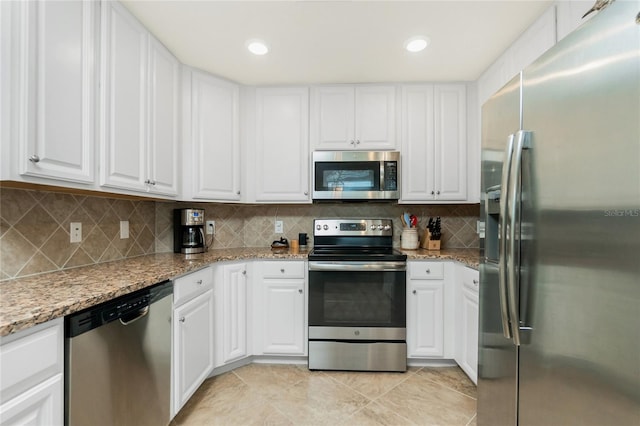 kitchen with stainless steel appliances, light stone counters, backsplash, and white cabinets