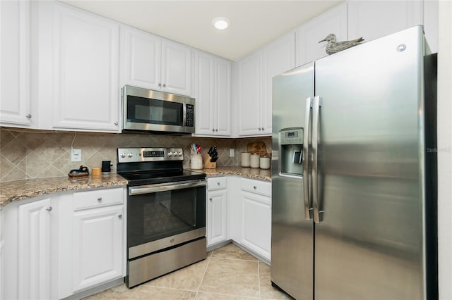 kitchen with light tile patterned floors, white cabinets, decorative backsplash, light stone counters, and stainless steel appliances