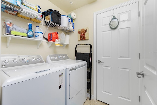 clothes washing area featuring laundry area, light tile patterned flooring, and washing machine and dryer