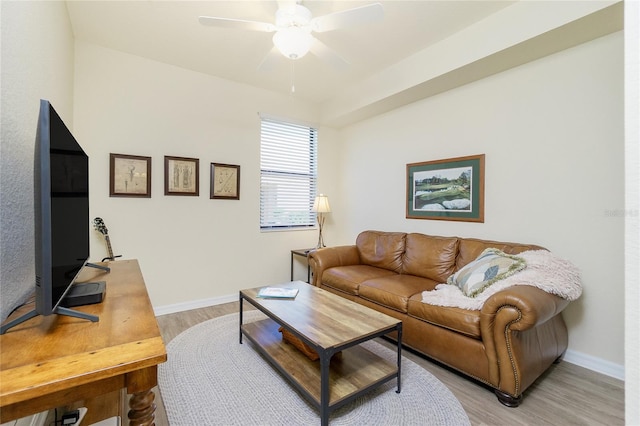 living room with light wood-type flooring, ceiling fan, and baseboards