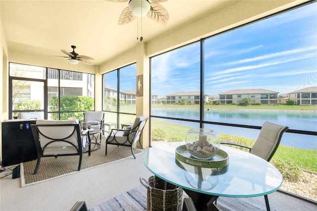 sunroom / solarium with a ceiling fan, a residential view, and a water view