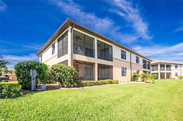 rear view of property featuring central AC unit, a ceiling fan, and a yard