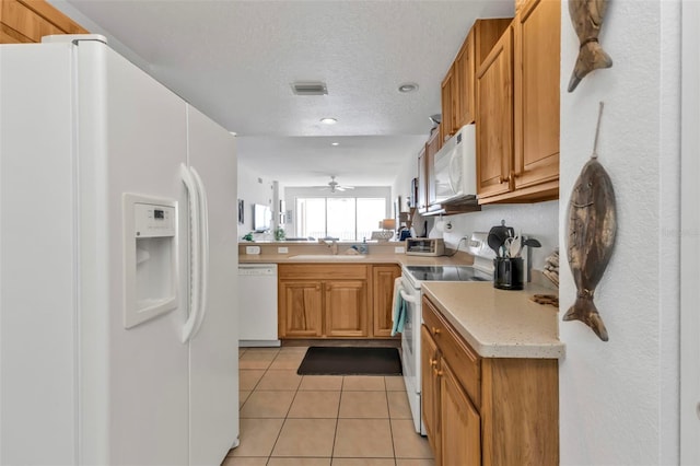 kitchen featuring light tile patterned floors, white appliances, a sink, visible vents, and light countertops