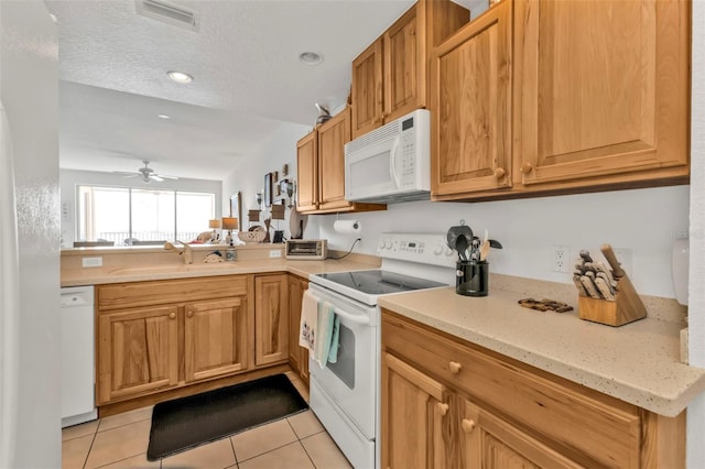 kitchen with light tile patterned floors, ceiling fan, a textured ceiling, white appliances, and a sink