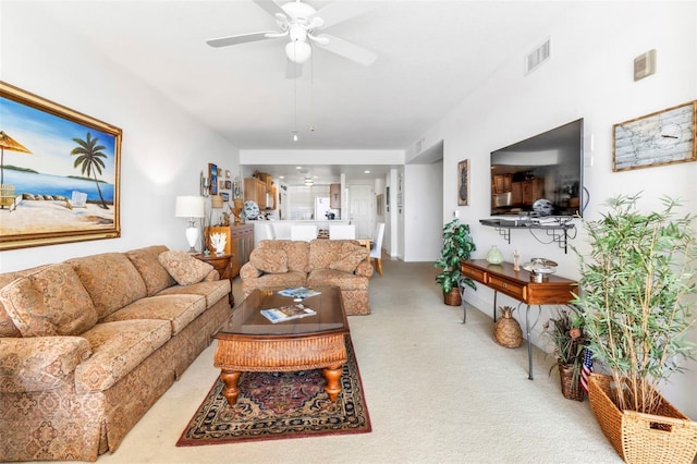 living room with ceiling fan, visible vents, and light colored carpet