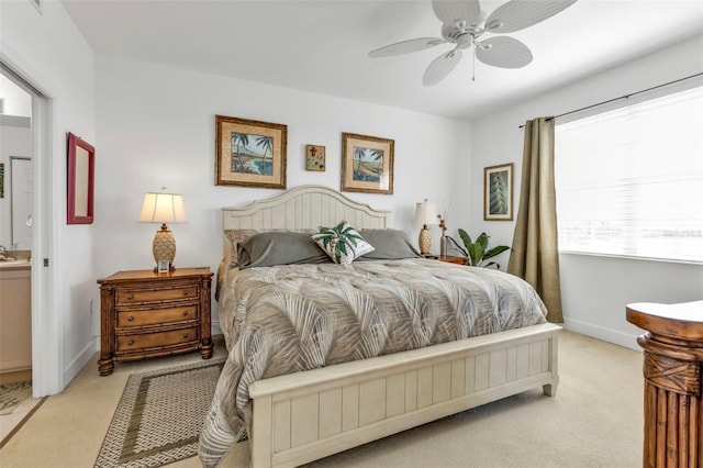 bedroom featuring ensuite bathroom, light colored carpet, a sink, a ceiling fan, and baseboards