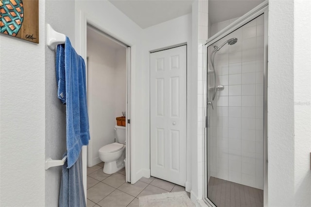 full bath featuring a stall shower, tile patterned flooring, a closet, and toilet