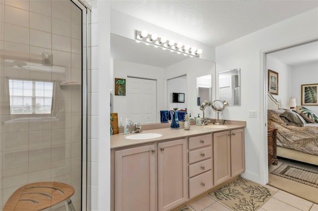 bathroom with a tile shower, double vanity, a sink, and tile patterned floors