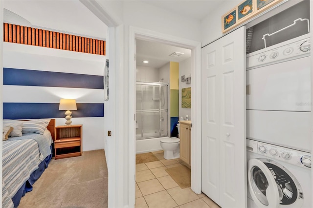 laundry room with laundry area, light tile patterned flooring, stacked washer and clothes dryer, and light colored carpet