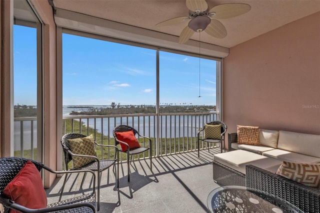 sunroom / solarium featuring a healthy amount of sunlight, a water view, and ceiling fan