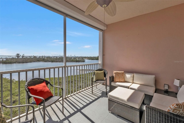 sunroom featuring a water view and a ceiling fan