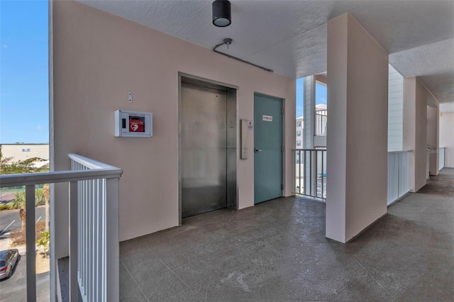 hallway with a textured ceiling and elevator