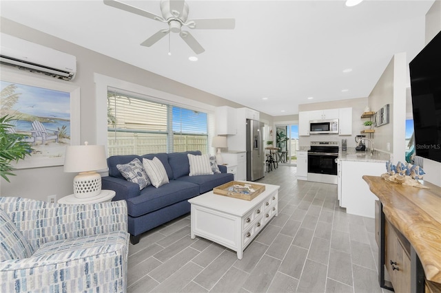 living area featuring a ceiling fan, recessed lighting, an AC wall unit, and wood finish floors