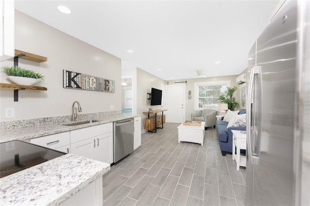 kitchen with a sink, white cabinetry, appliances with stainless steel finishes, open shelves, and a wall mounted air conditioner