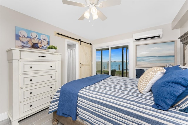 bedroom featuring access to exterior, a water view, a barn door, an AC wall unit, and ceiling fan